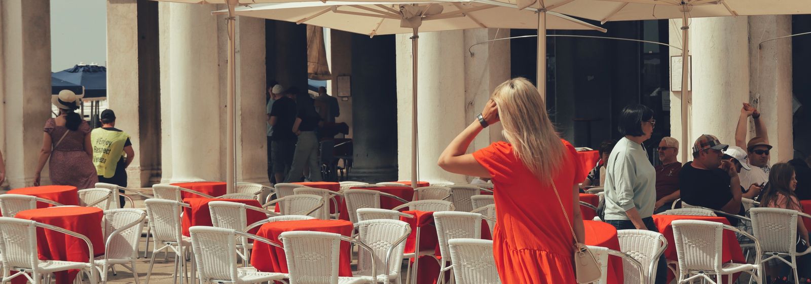 Femme élégante en robe avec valise dans une rue de Venise — valise d'été Vogue Française