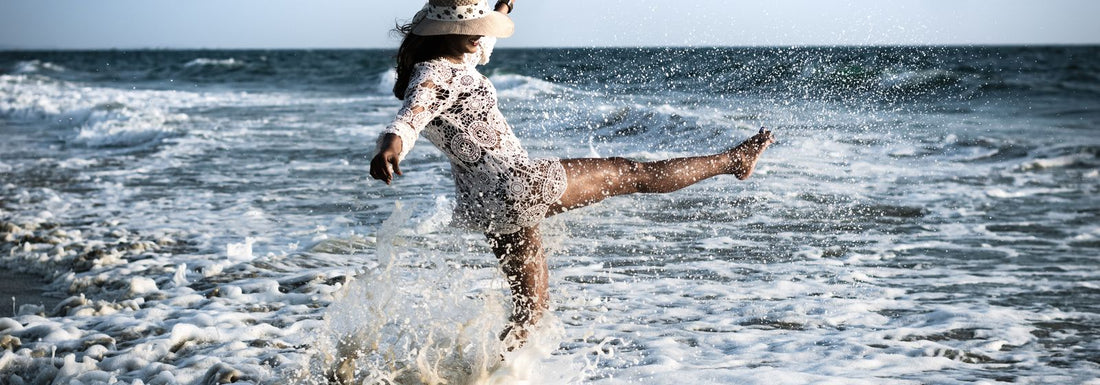 Femme en robe de plage crochet et chapeau au bord de la mer — tenue de plage Vogue Française